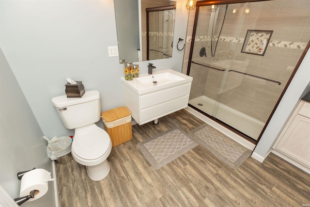 full bathroom featuring toilet, a shower stall, wood finished floors, and vanity