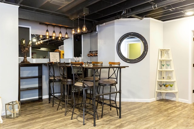 bar with a bar, baseboards, and wood finished floors