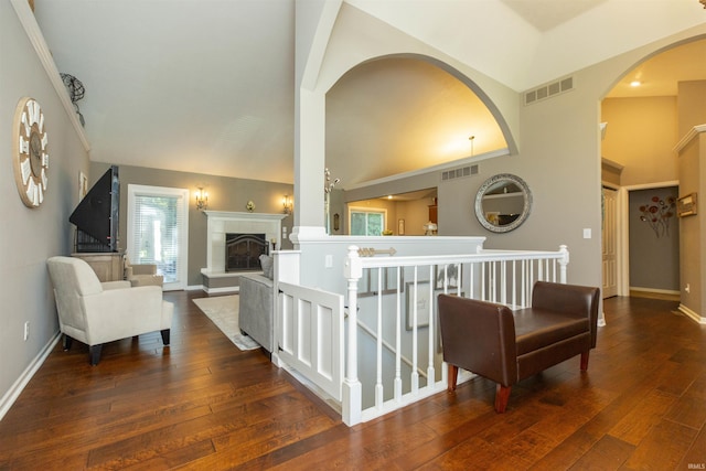 hall featuring visible vents, wood-type flooring, baseboards, and high vaulted ceiling