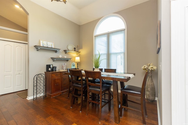 dining space with arched walkways, baseboards, vaulted ceiling, and wood finished floors