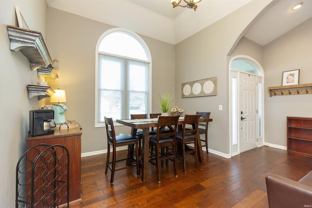dining space with arched walkways, baseboards, wood-type flooring, and lofted ceiling
