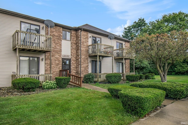 view of front of home with brick siding, a balcony, and a front yard