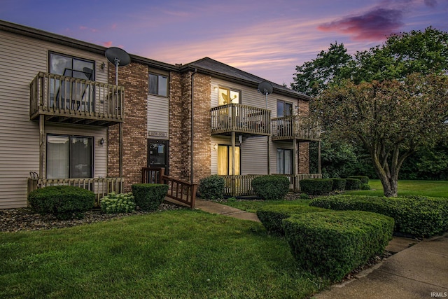 view of front of house with brick siding, a front lawn, and a balcony