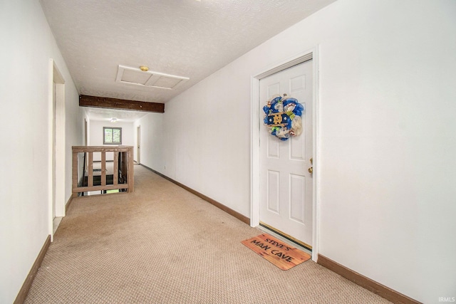 hall featuring baseboards, attic access, and an upstairs landing