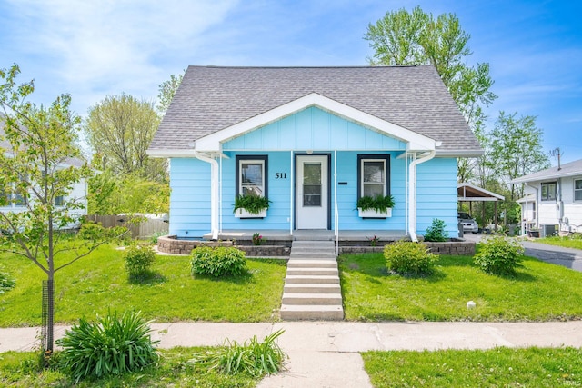 bungalow-style home with a porch, a front lawn, board and batten siding, and roof with shingles