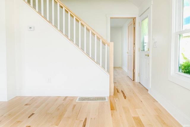entrance foyer featuring baseboards, visible vents, wood finished floors, and stairway