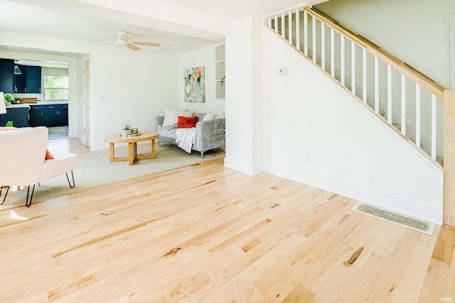 living area featuring visible vents, stairs, wood finished floors, baseboards, and ceiling fan