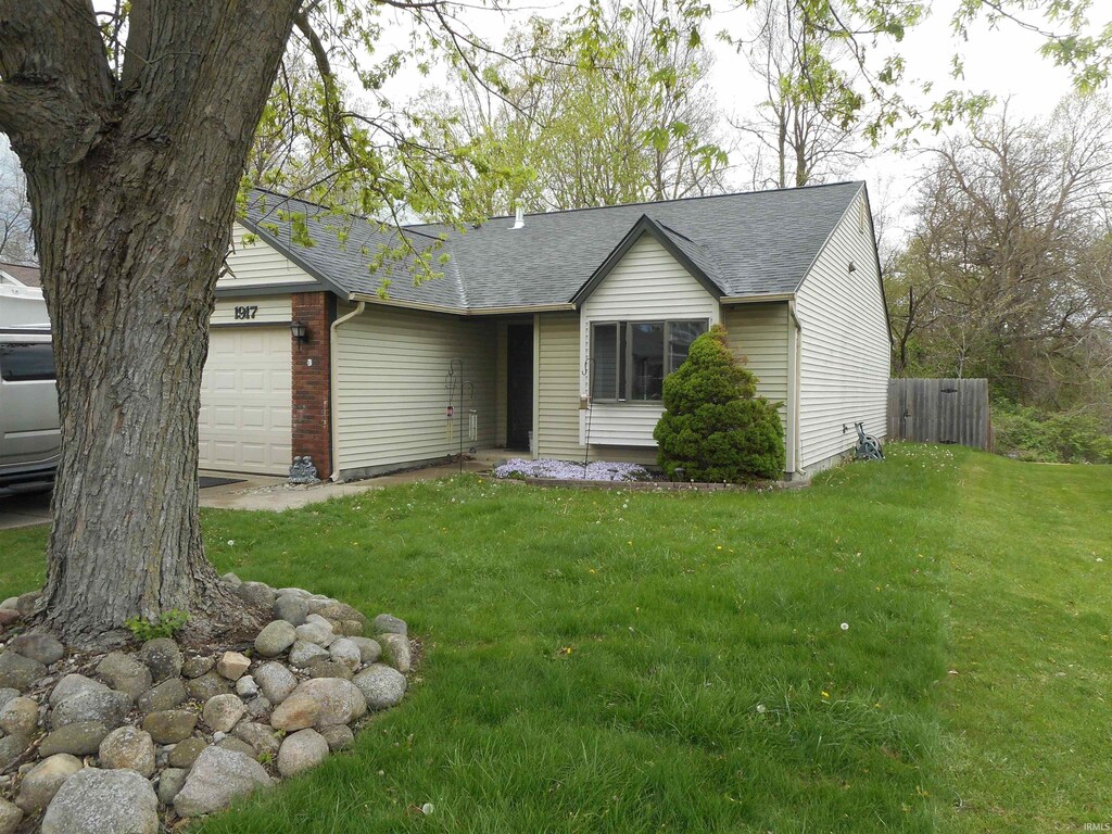 view of front facade with fence, a shingled roof, a front yard, and a garage