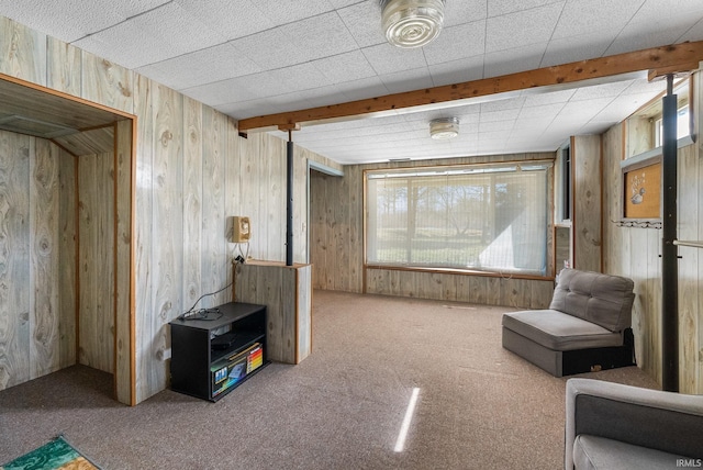 living area with wooden walls, carpet floors, and beamed ceiling