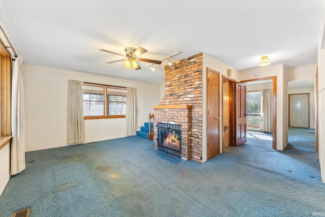 unfurnished living room featuring carpet floors, ceiling fan, a brick fireplace, and visible vents