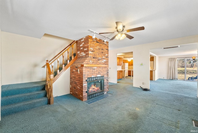 unfurnished living room with carpet floors, stairs, a fireplace, ceiling fan, and rail lighting