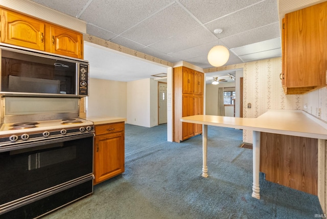 kitchen featuring dark carpet, a kitchen bar, light countertops, brown cabinets, and electric stove