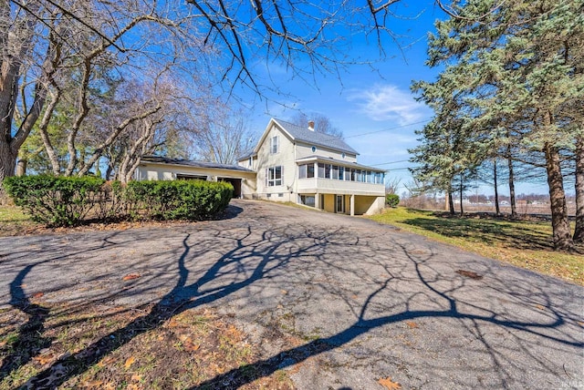 view of front facade featuring a chimney and aphalt driveway