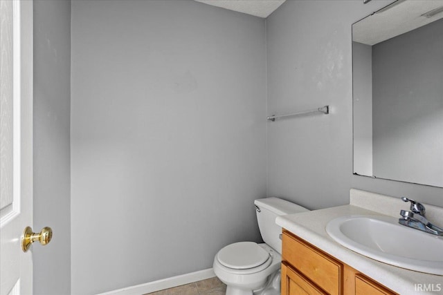 half bathroom with toilet, baseboards, tile patterned flooring, and vanity