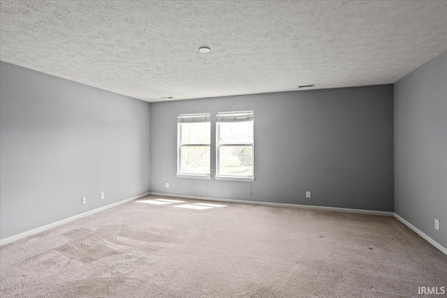 carpeted spare room featuring baseboards and a textured ceiling