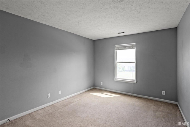 carpeted spare room with visible vents, a textured ceiling, and baseboards