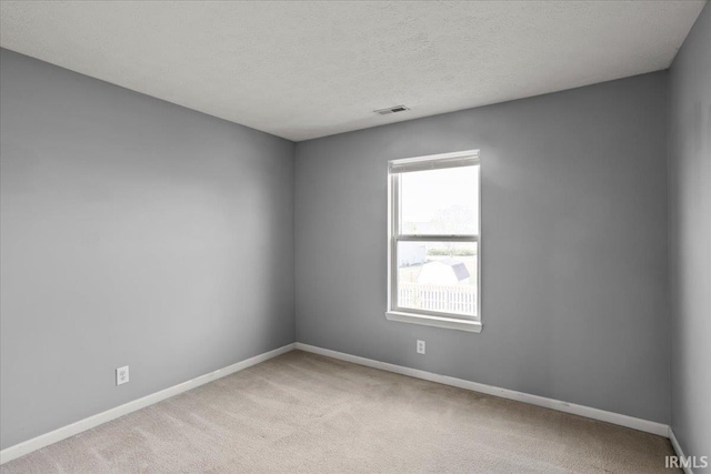 spare room with baseboards, carpet flooring, a textured ceiling, and visible vents