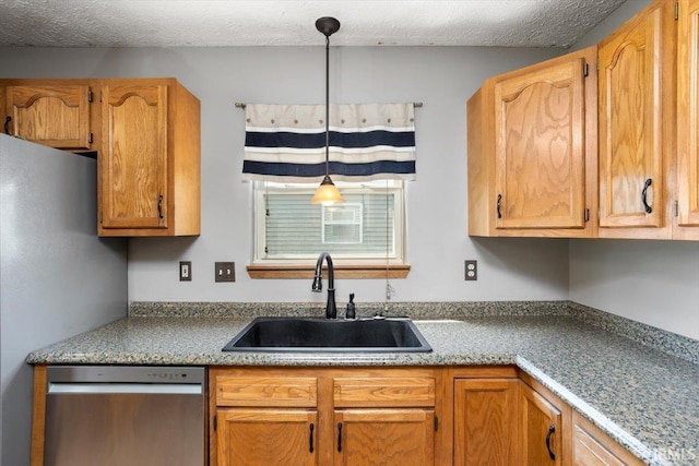 kitchen with a textured ceiling, decorative light fixtures, a sink, light countertops, and stainless steel appliances