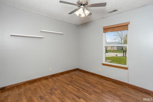 spare room with baseboards, a textured ceiling, wood finished floors, and visible vents