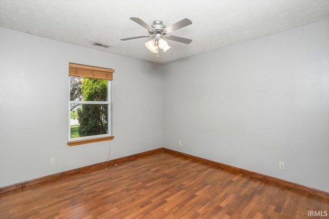 spare room with baseboards, ceiling fan, visible vents, and wood finished floors