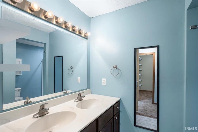 full bathroom featuring double vanity, a sink, and toilet