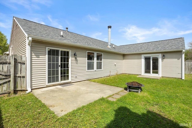 back of property with a lawn, fence, a patio area, and an outdoor fire pit