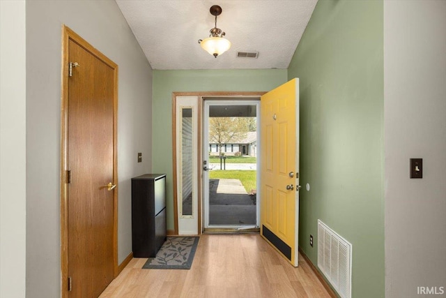 doorway to outside with baseboards, visible vents, and light wood finished floors