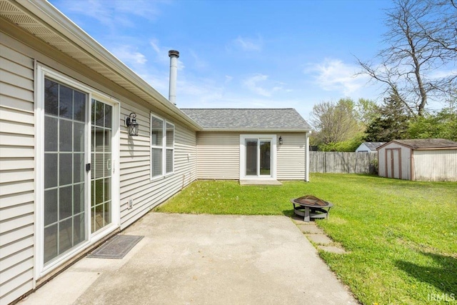 view of patio featuring a storage shed, fence, a fire pit, and an outdoor structure