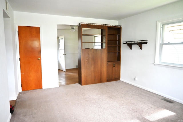 unfurnished room with carpet floors, a ceiling fan, baseboards, and visible vents