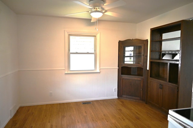 unfurnished dining area featuring baseboards, a ceiling fan, wood finished floors, and visible vents