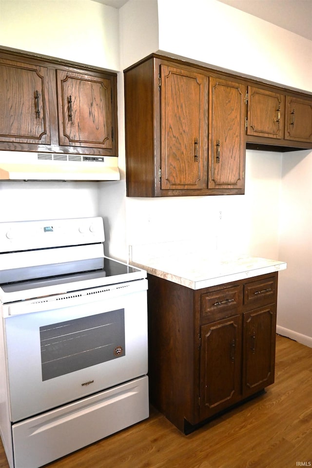 kitchen featuring wood finished floors, light countertops, electric range, and under cabinet range hood