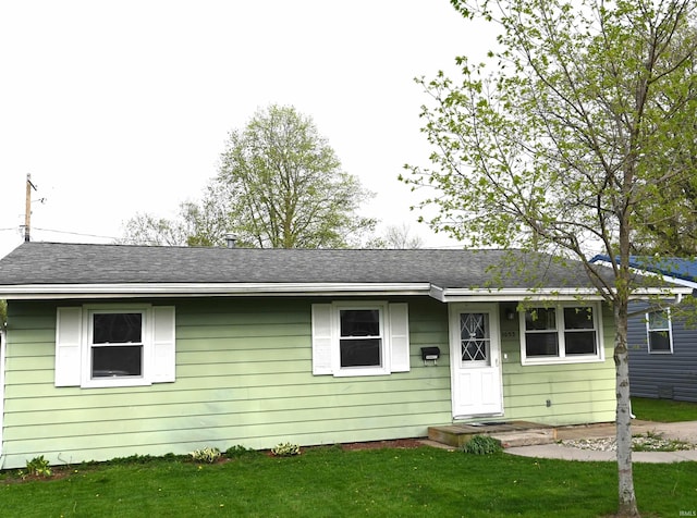 single story home featuring roof with shingles and a front lawn
