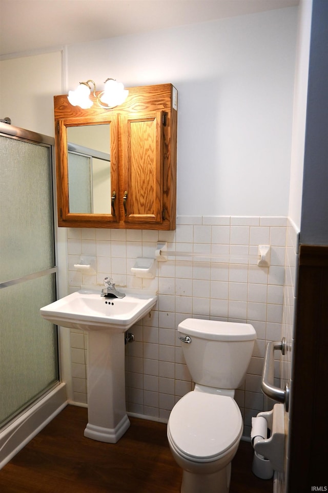 bathroom featuring a stall shower, wood finished floors, toilet, and tile walls