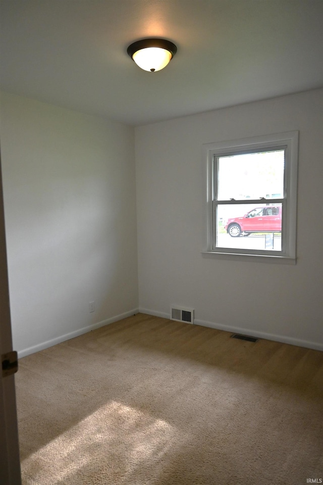 carpeted empty room with visible vents and baseboards