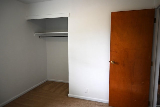 unfurnished bedroom featuring carpet floors, baseboards, and a closet