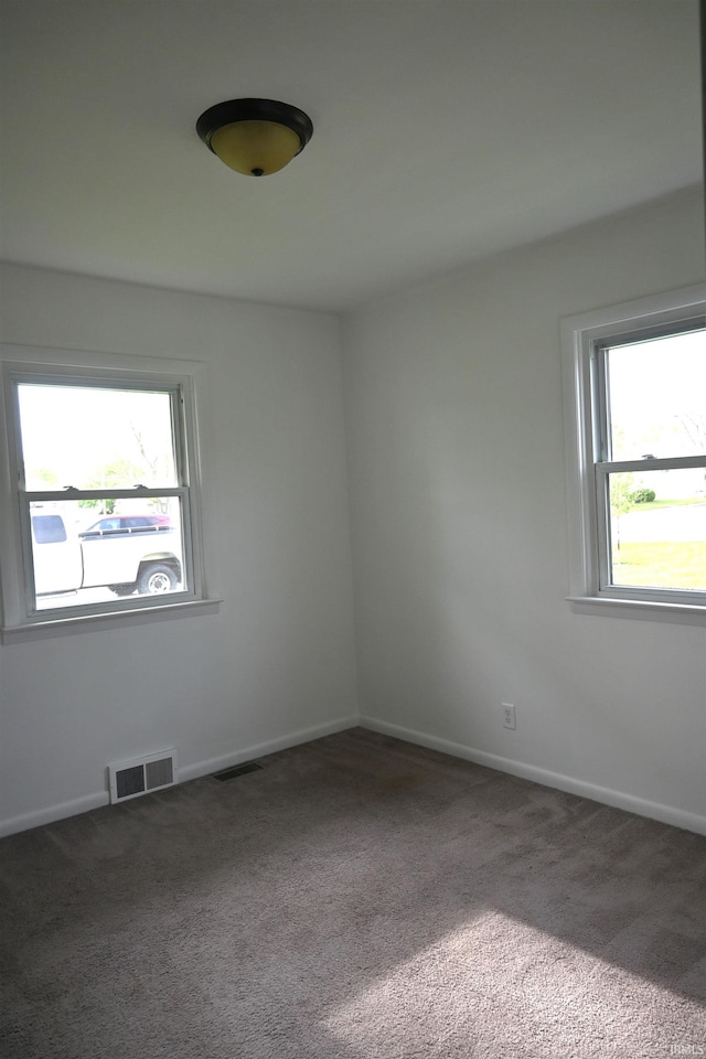 carpeted spare room with baseboards, plenty of natural light, and visible vents