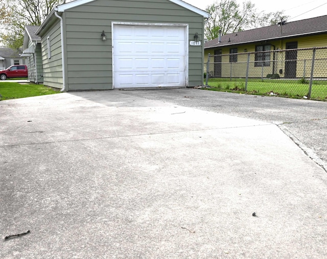 garage with fence and concrete driveway