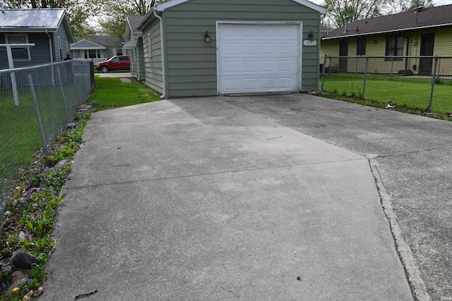 garage featuring fence and concrete driveway
