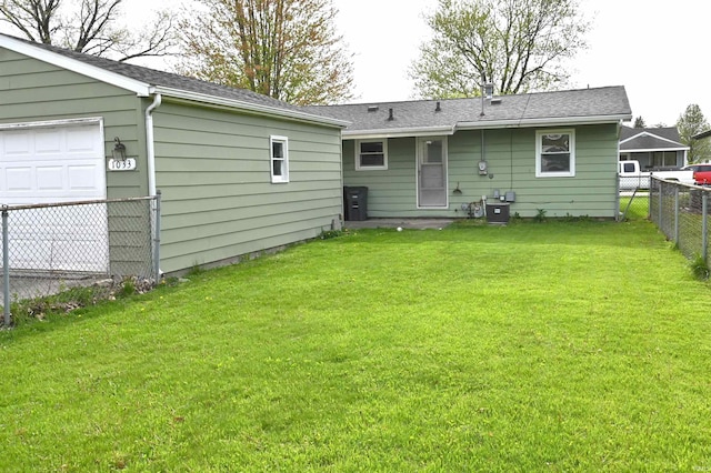 back of property featuring fence, a shingled roof, and a lawn
