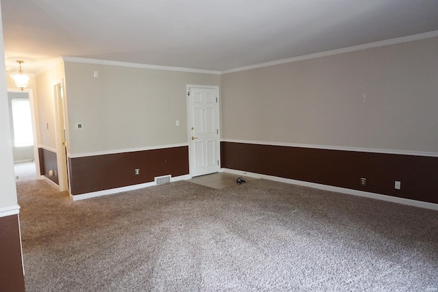 empty room featuring baseboards, ornamental molding, carpet flooring, and visible vents