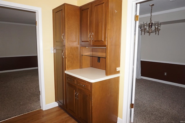 corridor featuring crown molding, wood finished floors, baseboards, carpet, and a notable chandelier