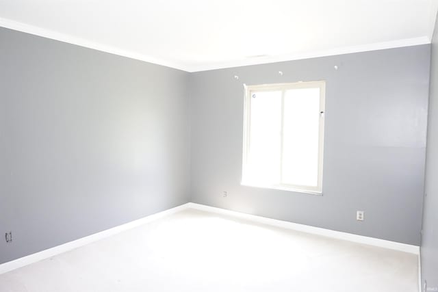empty room featuring baseboards, ornamental molding, and carpet