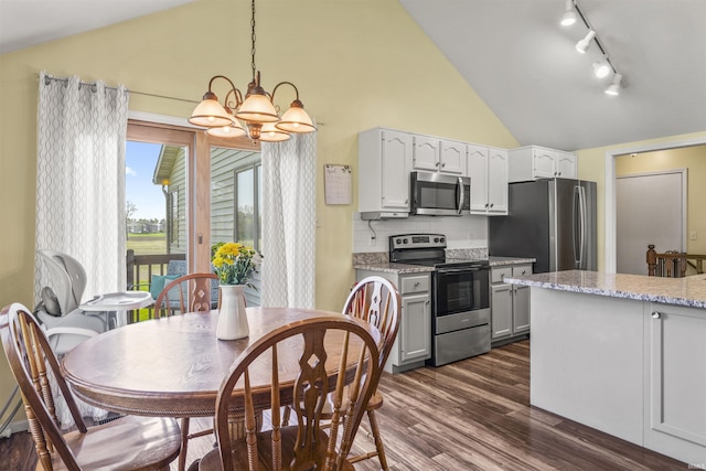 kitchen featuring appliances with stainless steel finishes, hanging light fixtures, dark wood finished floors, rail lighting, and a chandelier