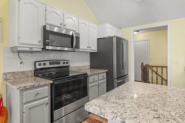 kitchen featuring lofted ceiling, backsplash, white cabinets, and stainless steel appliances