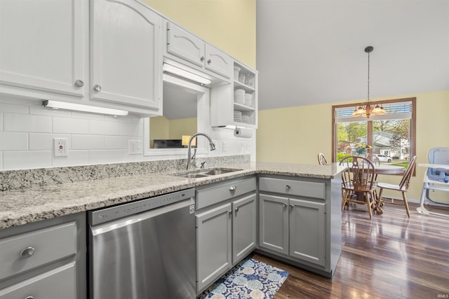kitchen featuring stainless steel dishwasher, gray cabinetry, a sink, a peninsula, and dark wood-style floors