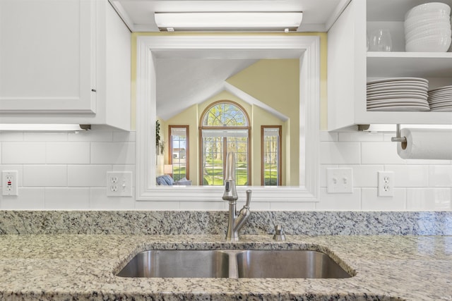 kitchen with white cabinets, light stone countertops, a sink, a wall mounted air conditioner, and backsplash