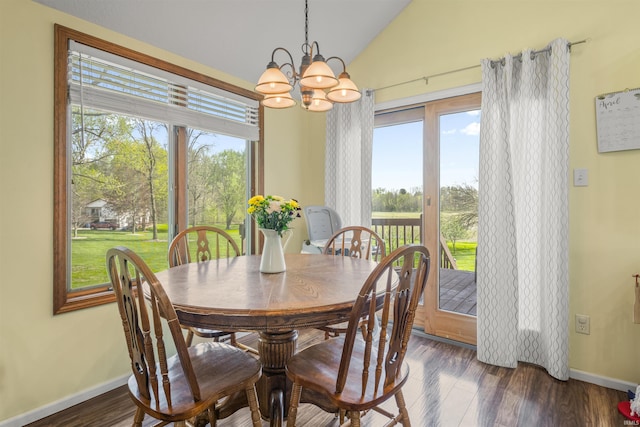 dining space featuring baseboards, a chandelier, vaulted ceiling, and wood finished floors