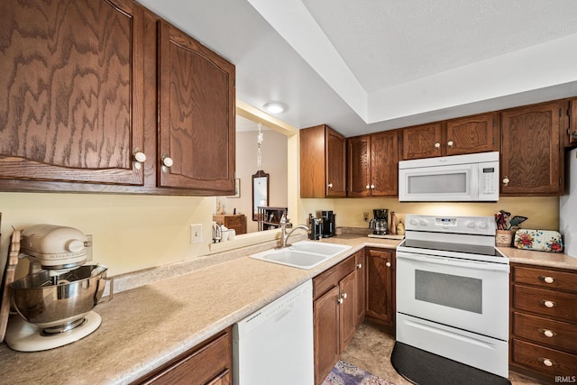 kitchen with a sink, brown cabinets, white appliances, and light countertops