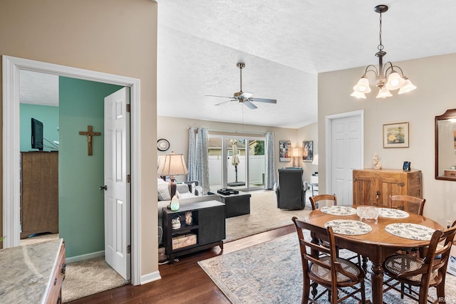 dining area featuring dark wood-style flooring, a textured ceiling, ceiling fan with notable chandelier, baseboards, and lofted ceiling