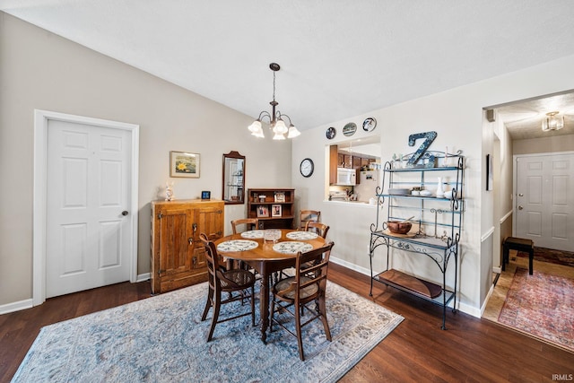 dining room with baseboards, an inviting chandelier, wood finished floors, and vaulted ceiling